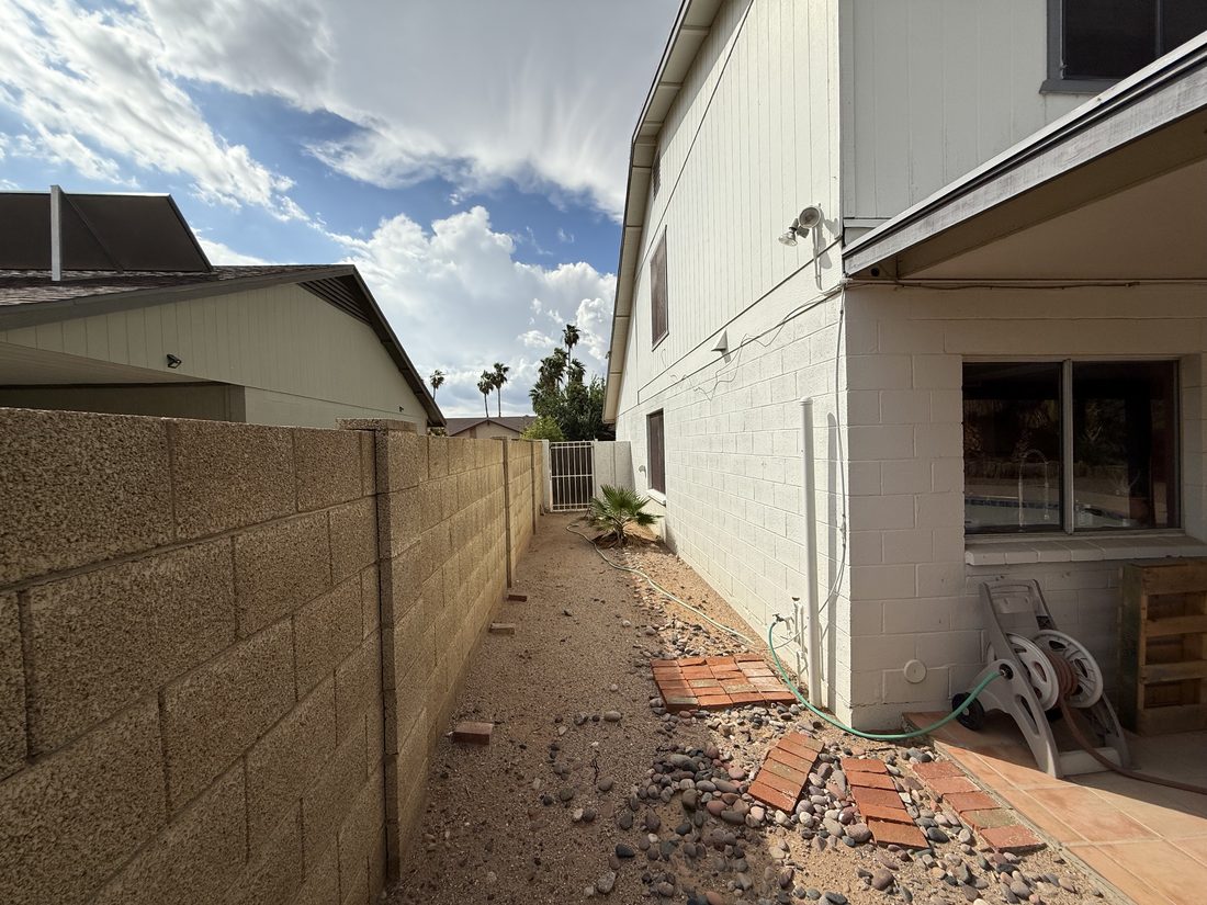The side yard of a house Honeybird Homes bought as-is, with visible wear and debris.